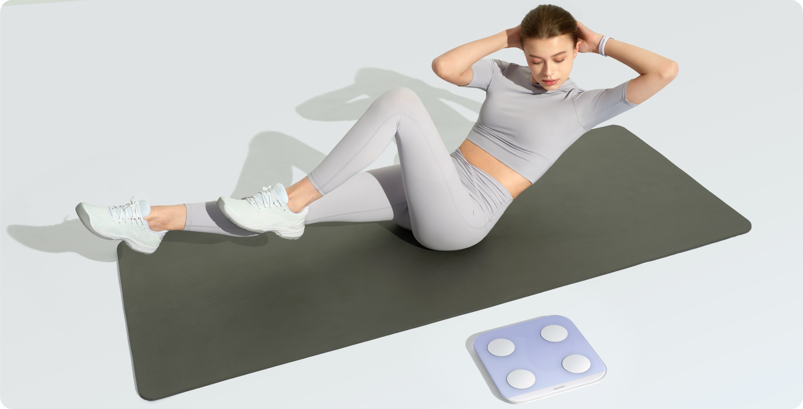 一个女人在华为智能体脂秤 3 蓝牙版旁边的瑜伽垫上做空中单车训练