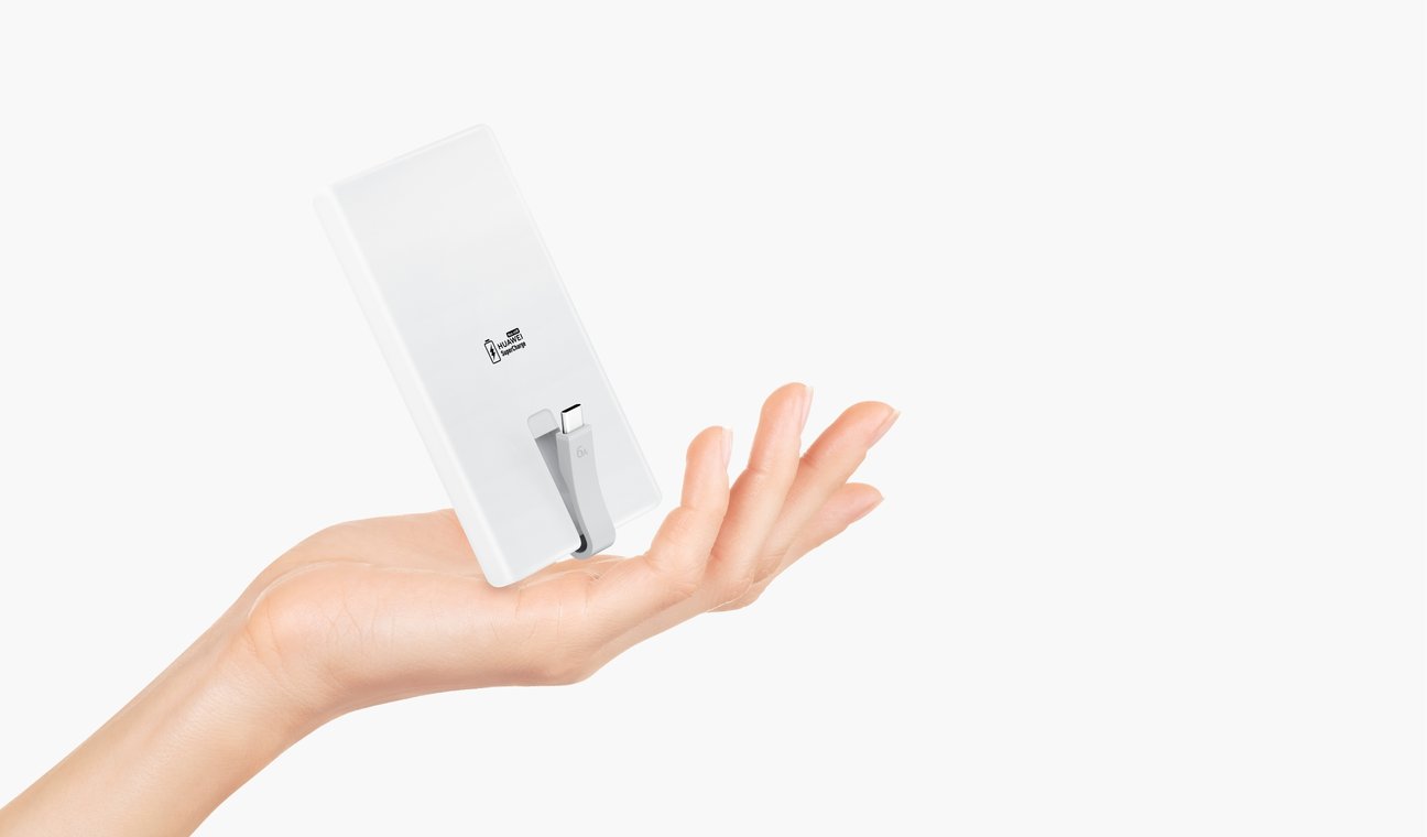 单手轻松托举华为自带线全能充移动电源（66W 12000），展示了其轻快便携的特点