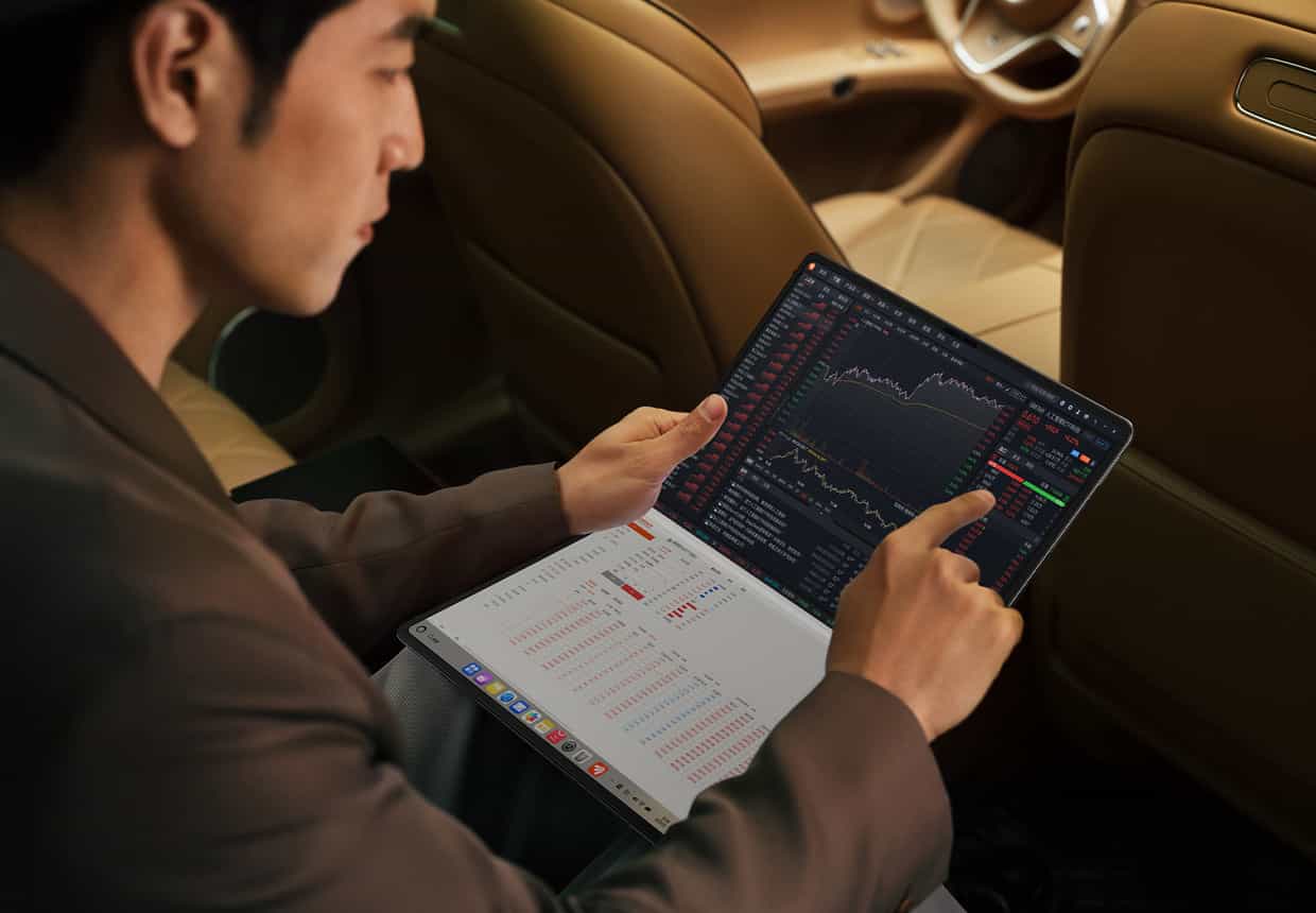 男人在汽车上使用 HUAWEI MateBook Fold 非凡大师跟踪股市，上屏显示股价信息，下屏显示股票信息