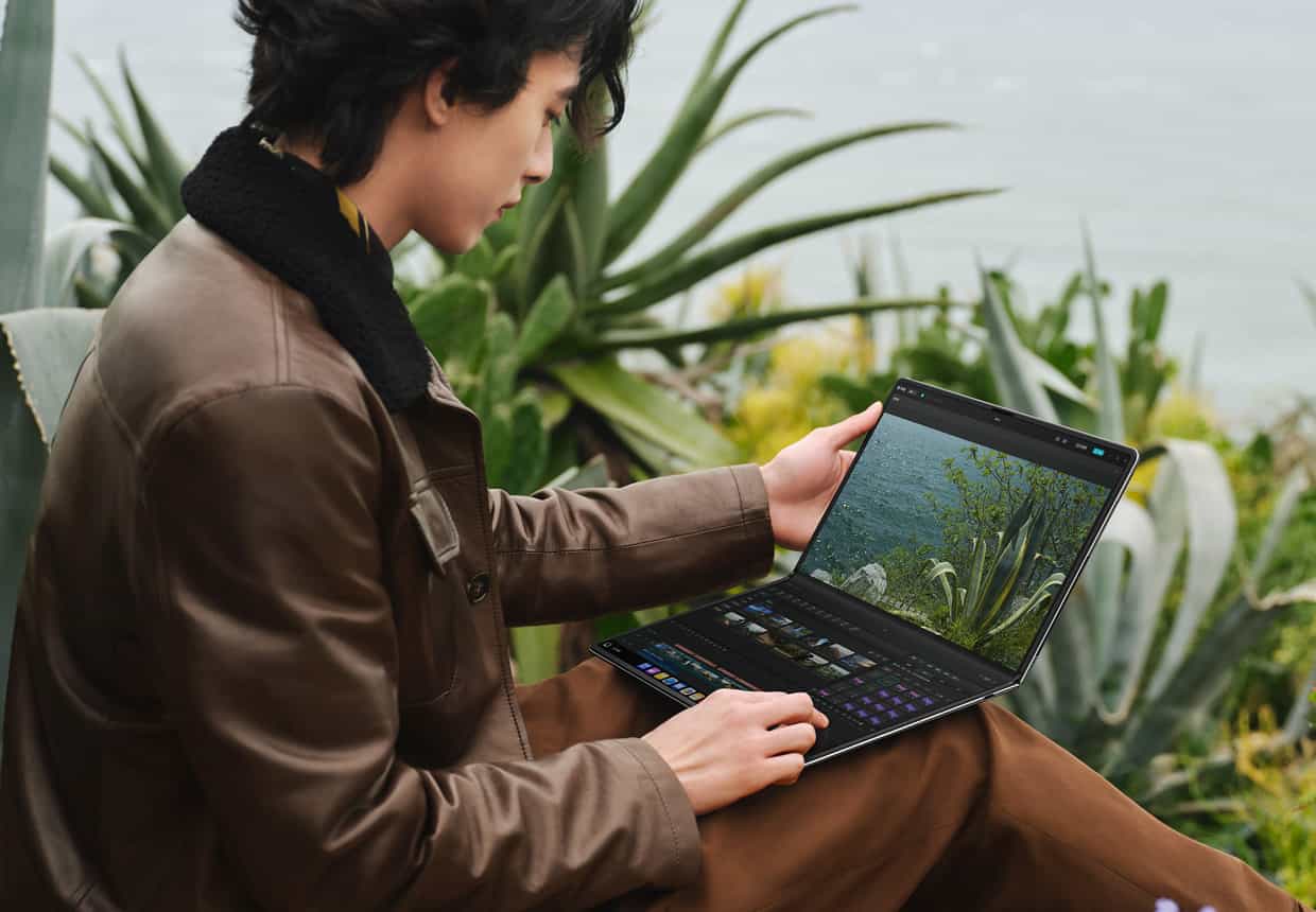 一个男人在户外使用 HUAWEI MateBook Fold 非凡大师剪辑视频，上屏是视频预览，下屏显示剪辑轨道