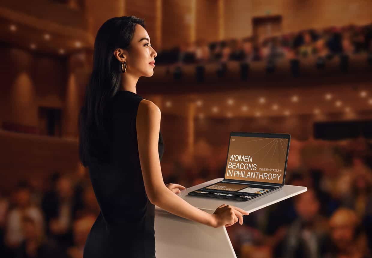 女人使用折叠态的 HUAWEI MateBook Fold 非凡大师进行演讲，电脑上屏显示演示文档，下屏显示题词和预览后续的幻灯片内容