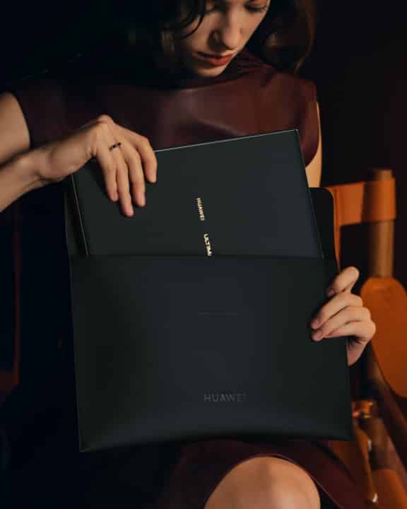 一个女人正在把 HUAWEI MateBook Fold 非凡大师装进华为折叠电脑尊享收纳包
