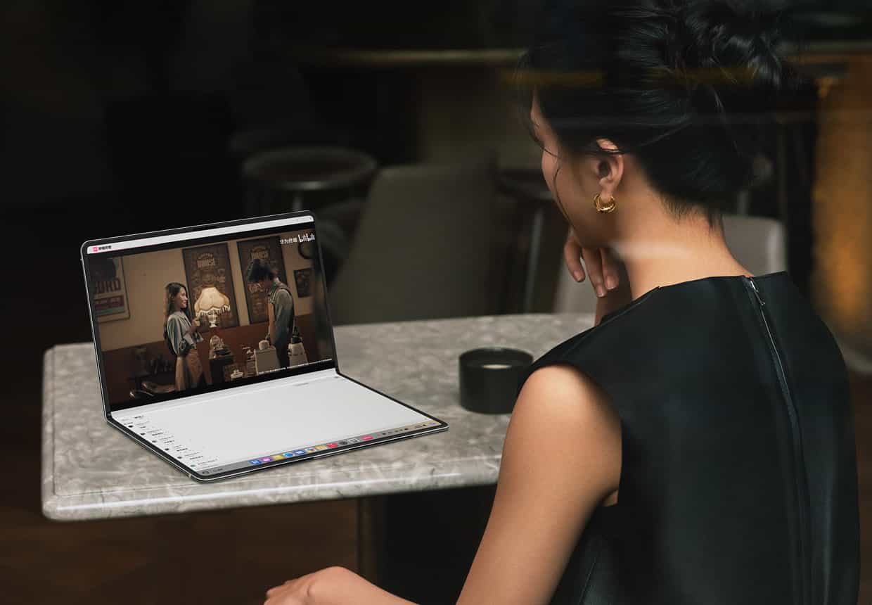 一个女人使用折叠态的 HUAWEI MateBook Fold 非凡大师观看影片，上屏是影片内容，下屏显示视频的评论