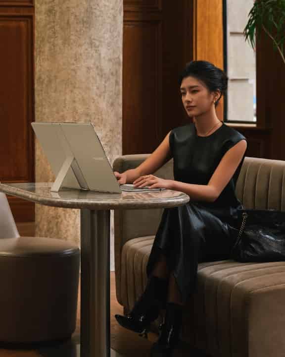 一个女人坐在椅子上，横屏使用 HUAWEI MateBook Fold 非凡大师和华为星跃随行键盘