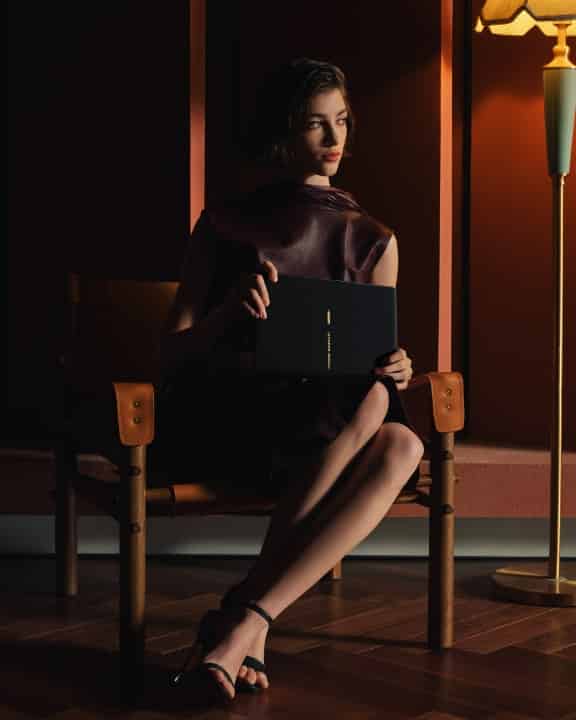 一个女人坐在椅子上，手拿 HUAWEI MateBook Fold Ultimate Design 非凡大师