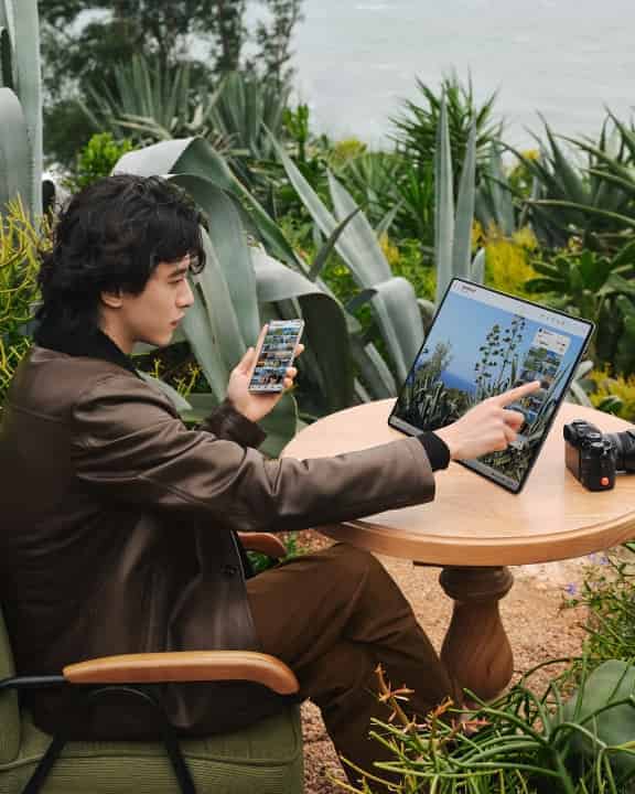 一个男人用手指操作 HUAWEI MateBook Fold 非凡大师屏幕上的手机镜像画面