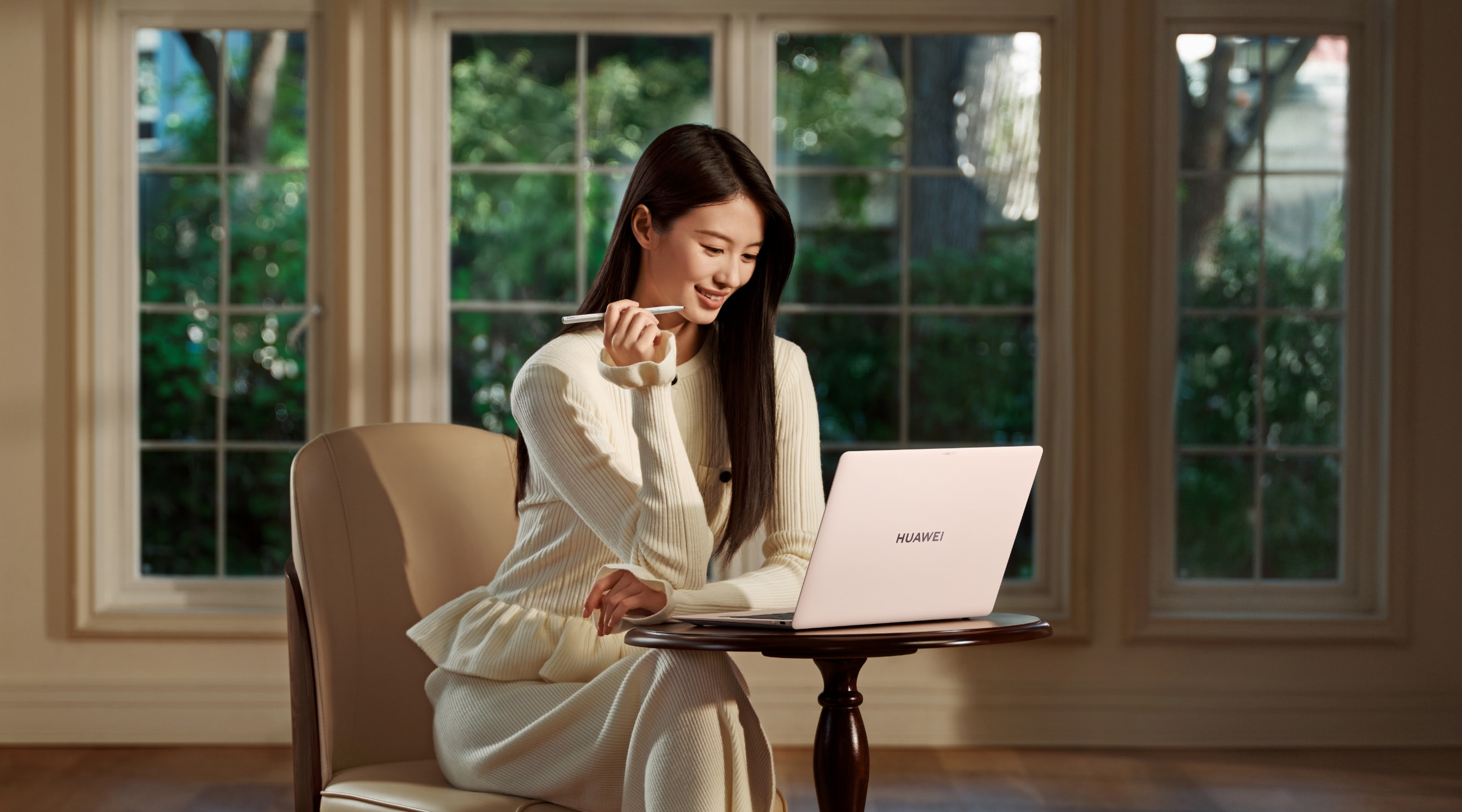 HUAWEI MateBook Pro 的创拍图，一名女性拿着手写笔正在注视产品