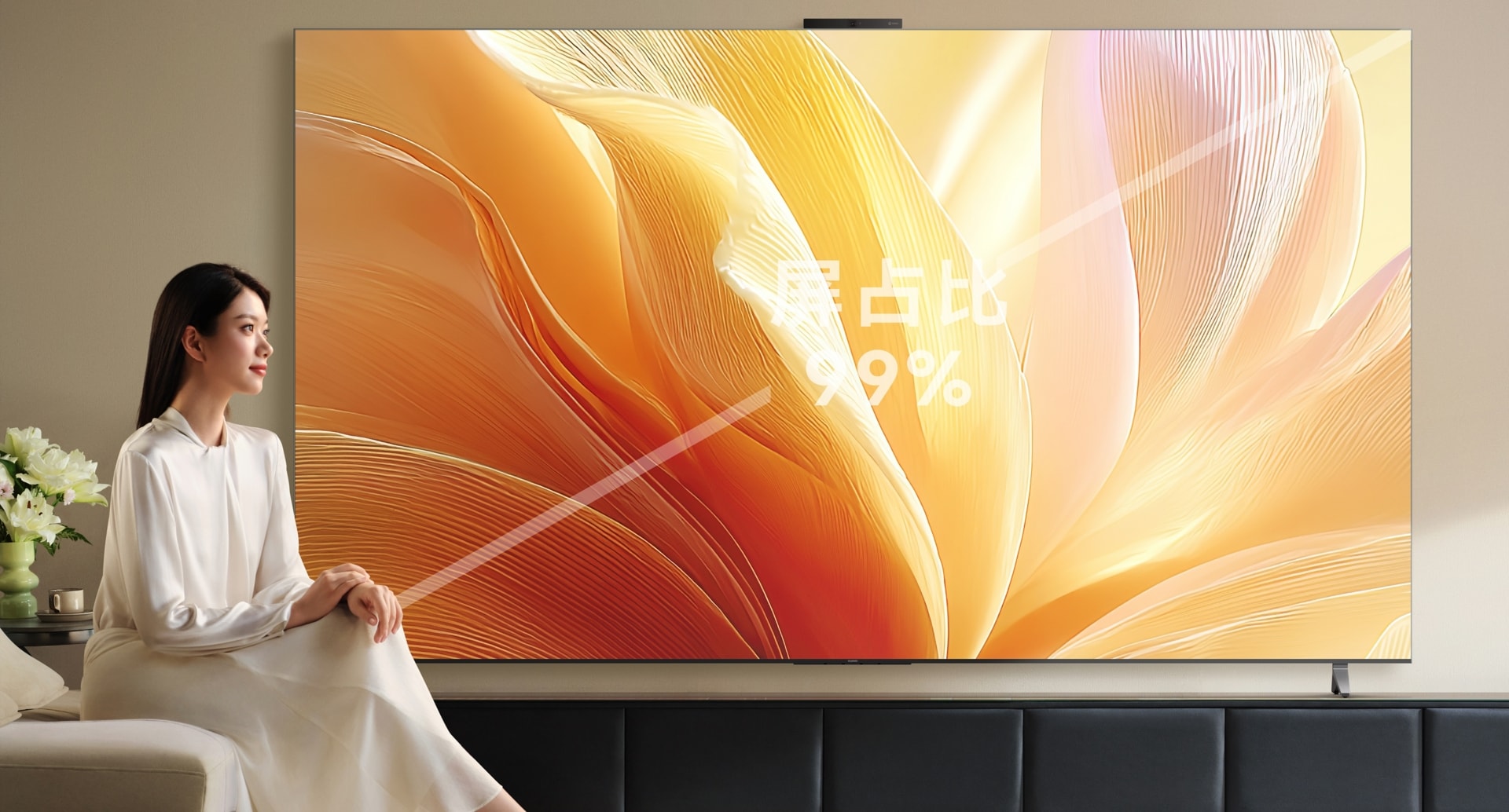 用户坐在华为 Vision 智慧屏 5 Pro 旁观看，展示了华为 Vision 智慧屏 5 Pro 99% 屏占比的巨幕效果。