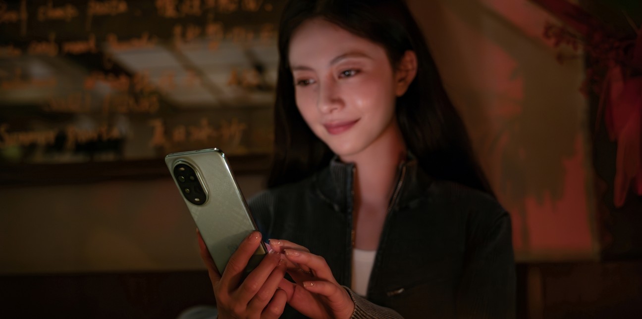 女性模特在暗光环境下使用 HUAWEI nova 13 Pro,展示屏幕 AI 护眼功能