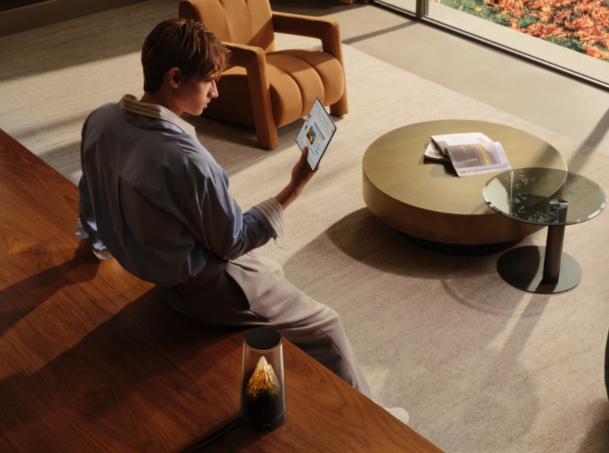 男子手持电子设备在家中上网，展示了华为路由 X3 Pro 日照金山 Wi-Fi 7+ 的疾速性能