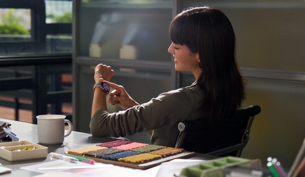 一个女人坐在座位上，通过手腕上佩戴的 HUAWEI WATCH 5 体验一些趣味的交互小游戏