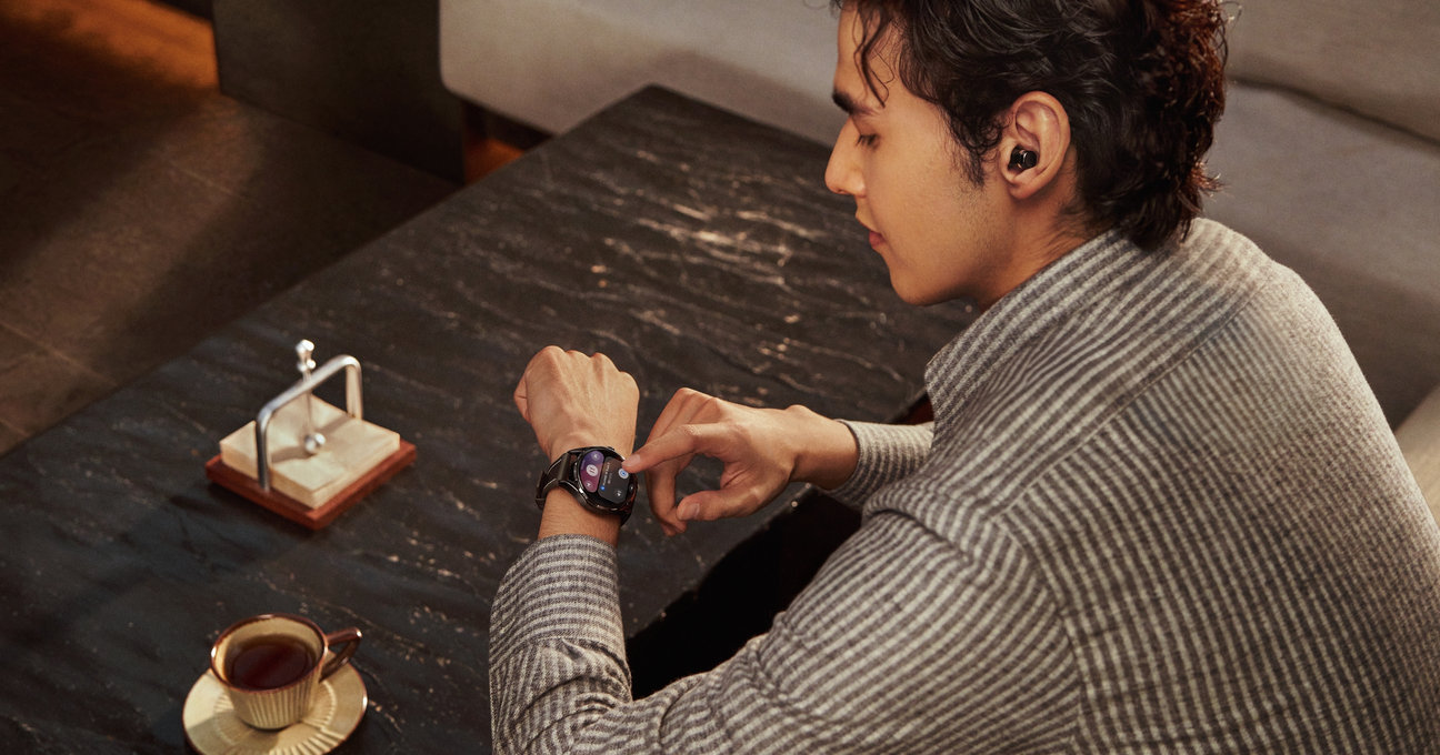 一位男士佩戴 HUAWEI WATCH Buds 2 耳机，同时在手腕上操作手表的图片，展示了手表上操控耳机的体验