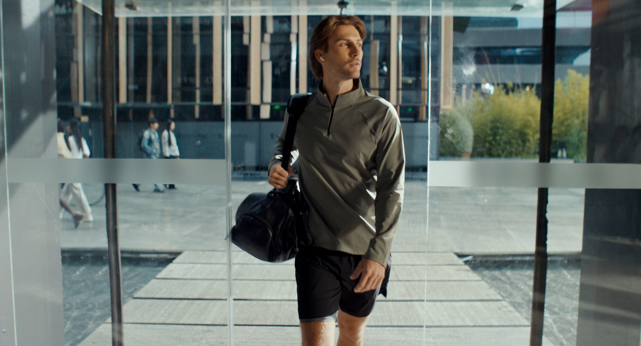 A man wearing Huawei earphones, showing Adaptive Audio feature on Huawei Audio Connect for a better listening experience