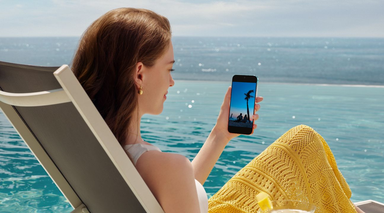 A female is sitting by the seaside with HUAWEI Pura 90s Pro Max in hand, show the 6000mah long battery life