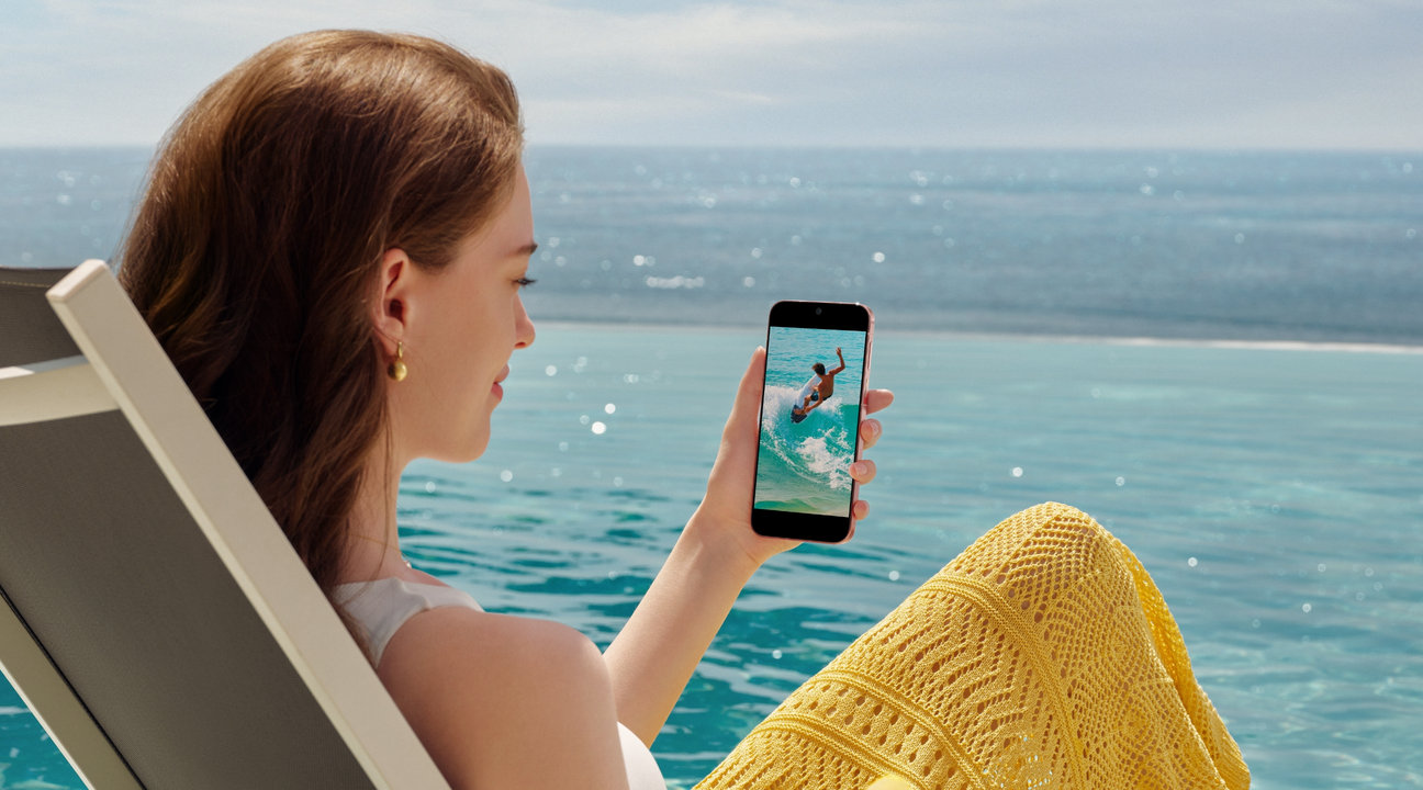 A female is sitting by the seaside with HUAWEI Pura 90s Pro in hand, show the 6000mah long battery life
